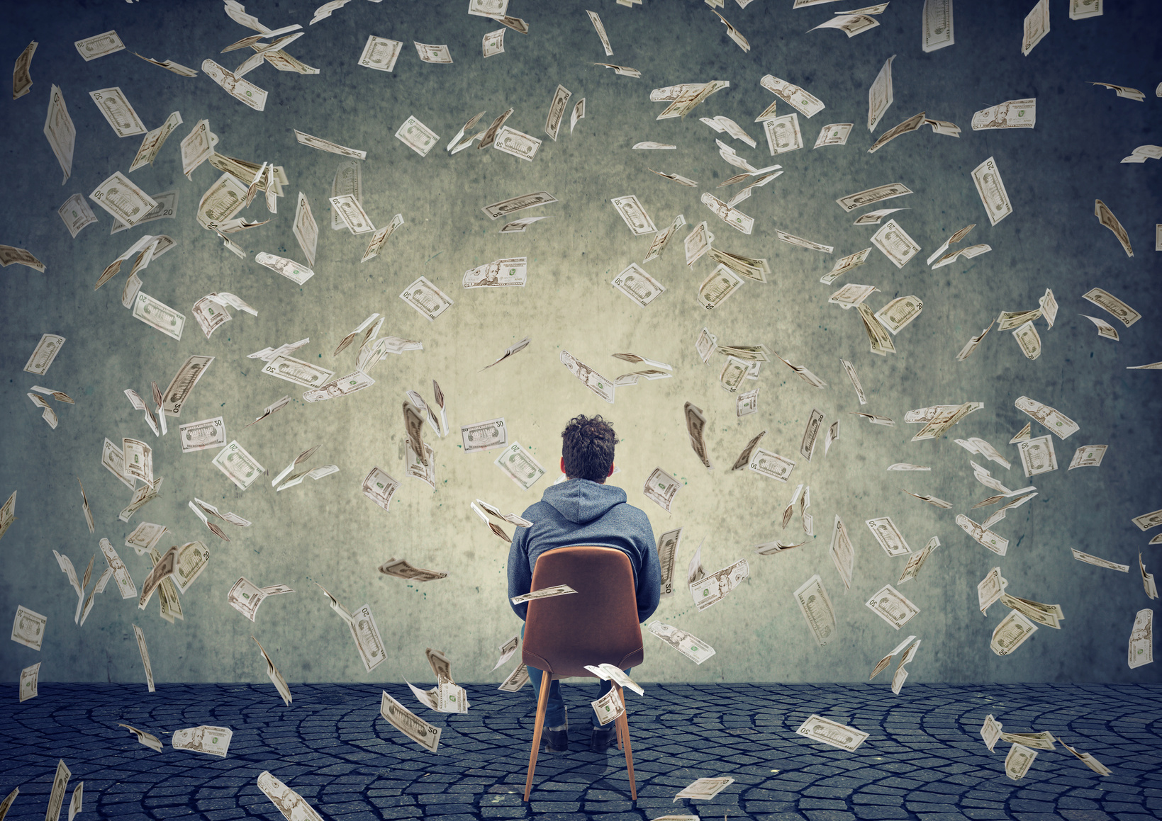 man sitting on chair in front of a wall under money rain